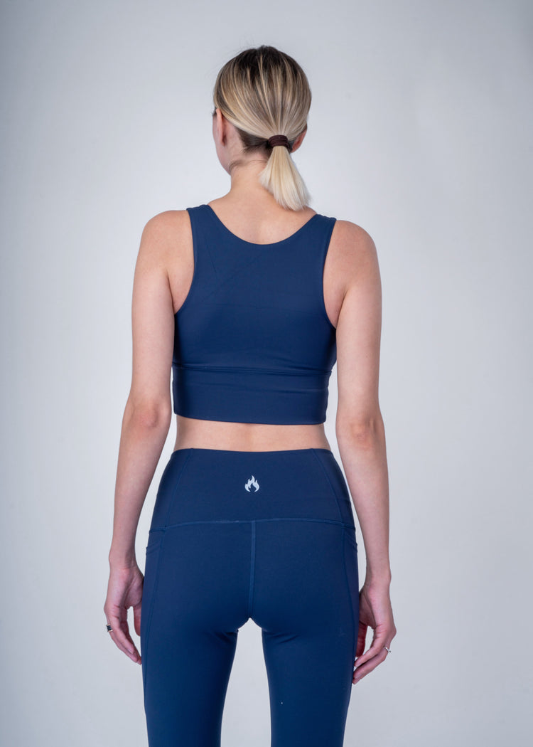 Person wearing a navy blue athletic outfit, a Bra, and Leggings on a plain background