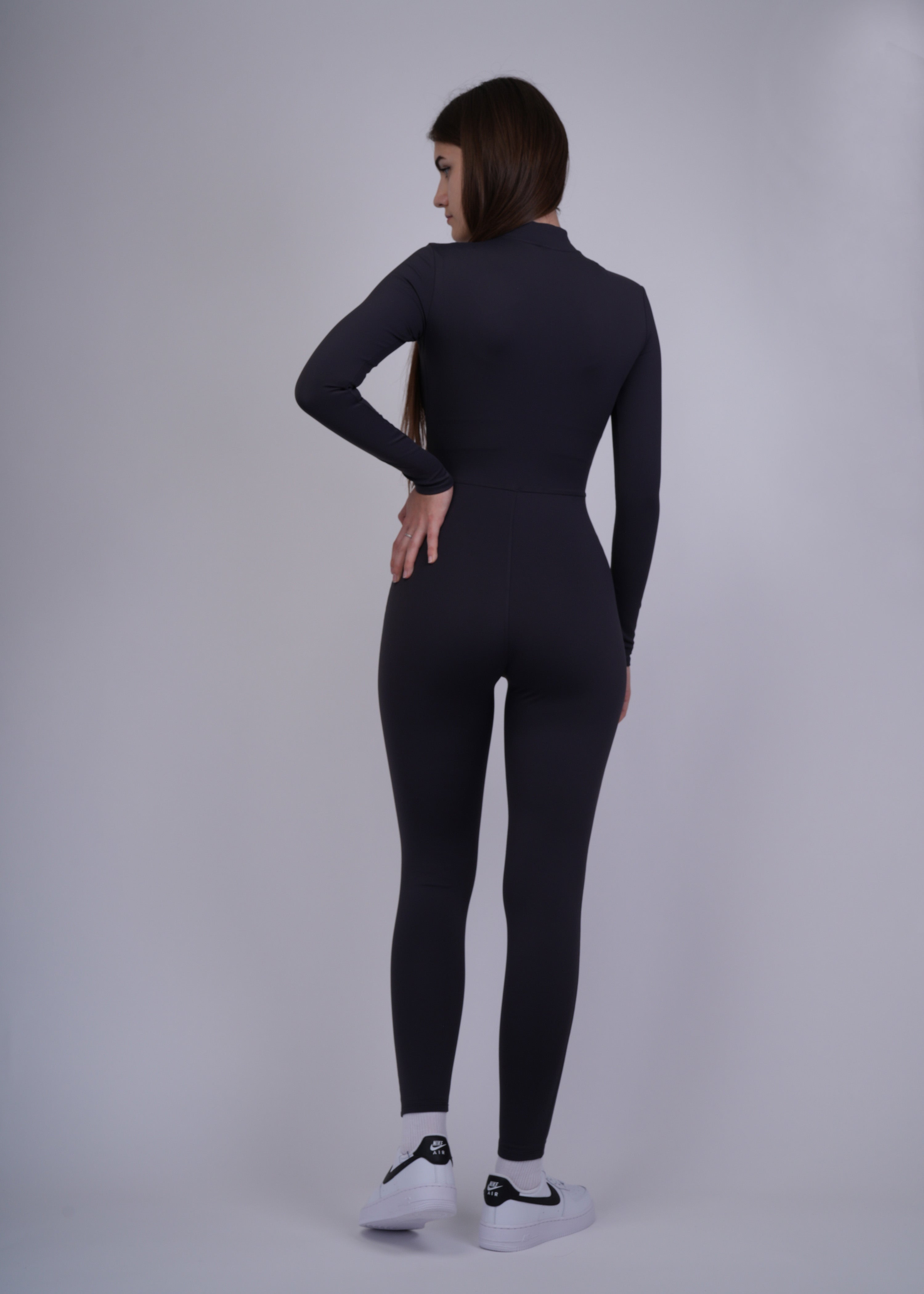A model wearing a black bodysuit on a plain background