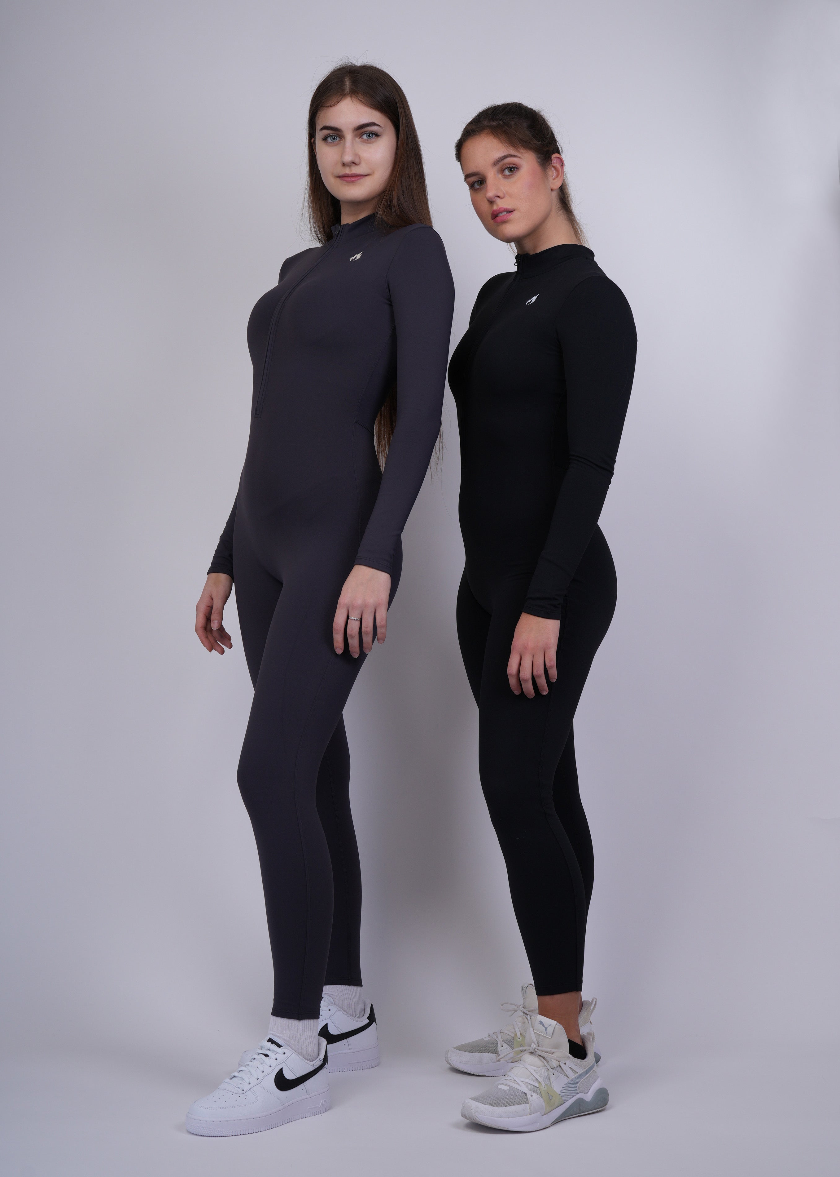 Two Models wearing black and graphite  full-body suits on a white background 