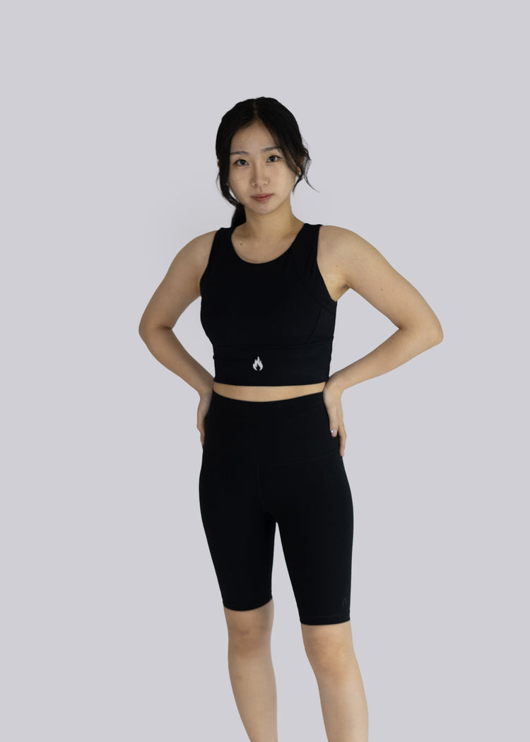 Woman wearing a black athletic outfit on a light gray background