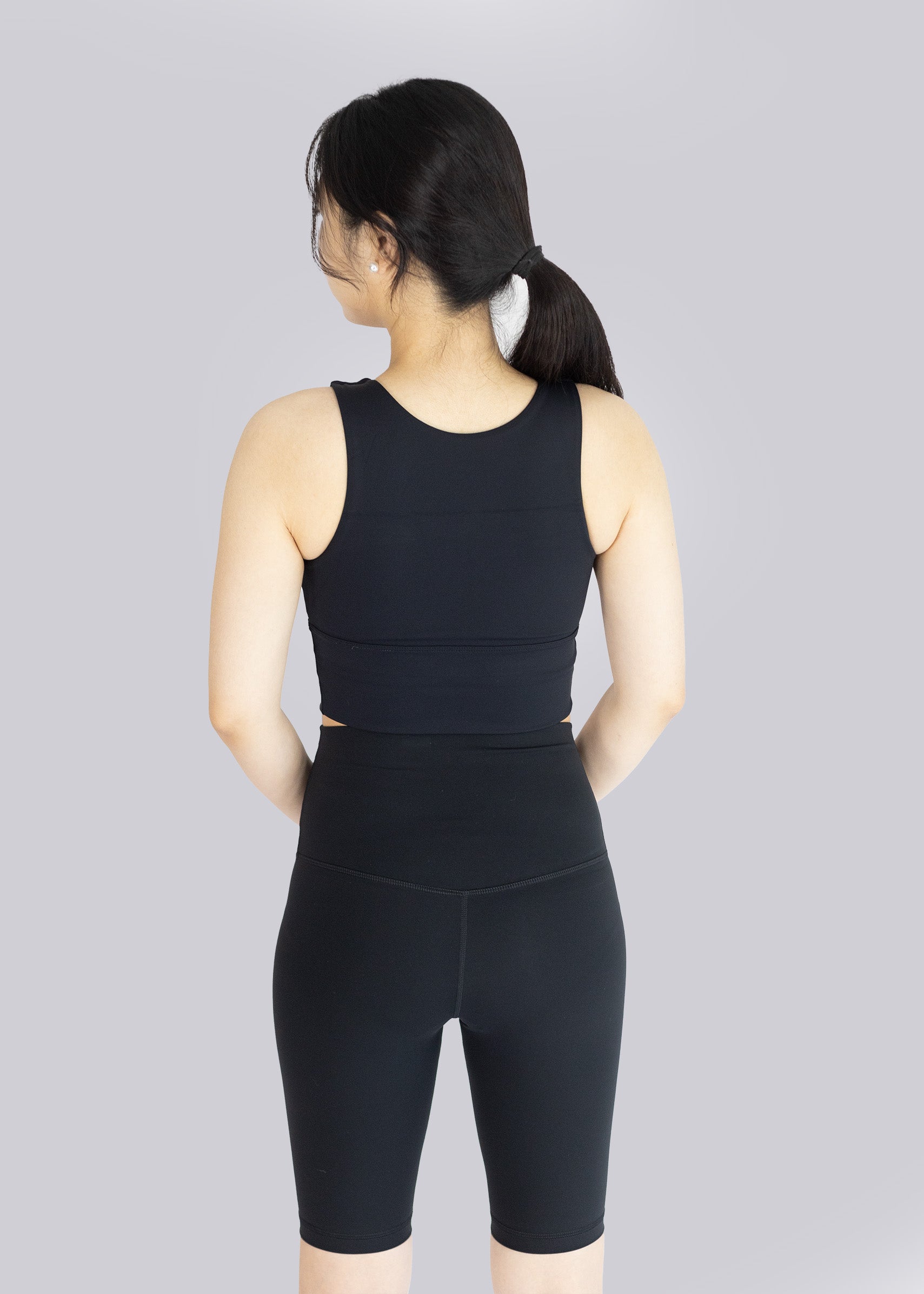 Woman wearing a black athletic outfit on a gray background