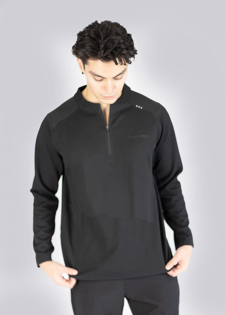 Man wearing a black long-sleeve athletic sweater on a gray background